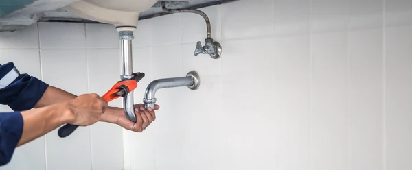 Ouvrier plombier-chauffagiste en combinaison de travail installant un système de chauffage par le sol dans un bâtiment en construction