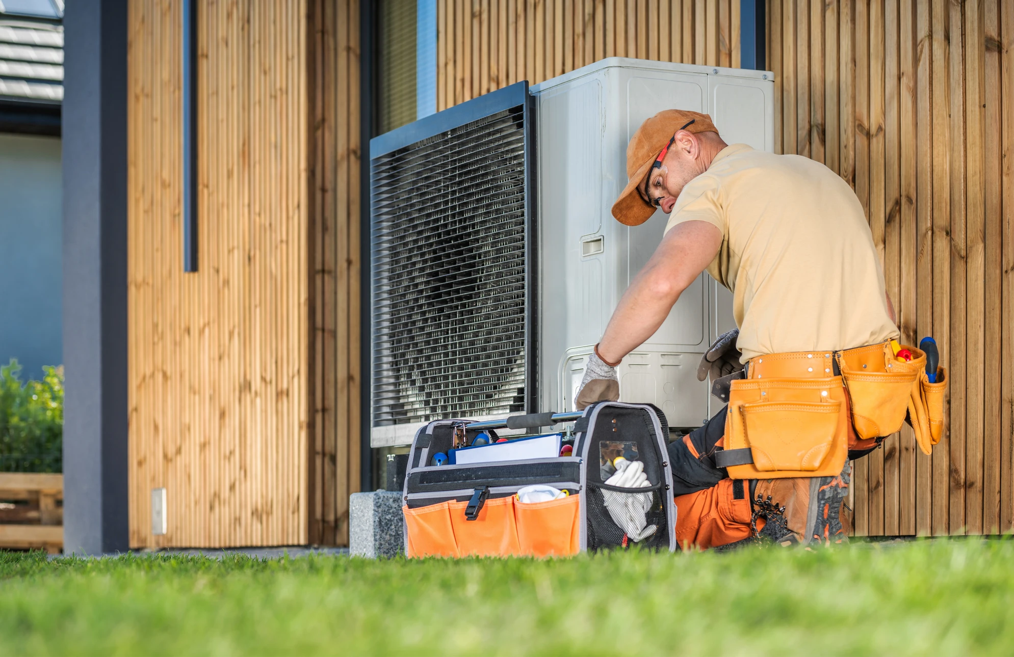 Un technicien d'ACC travaillant sur une pompe à chaleur moderne devant un immeuble