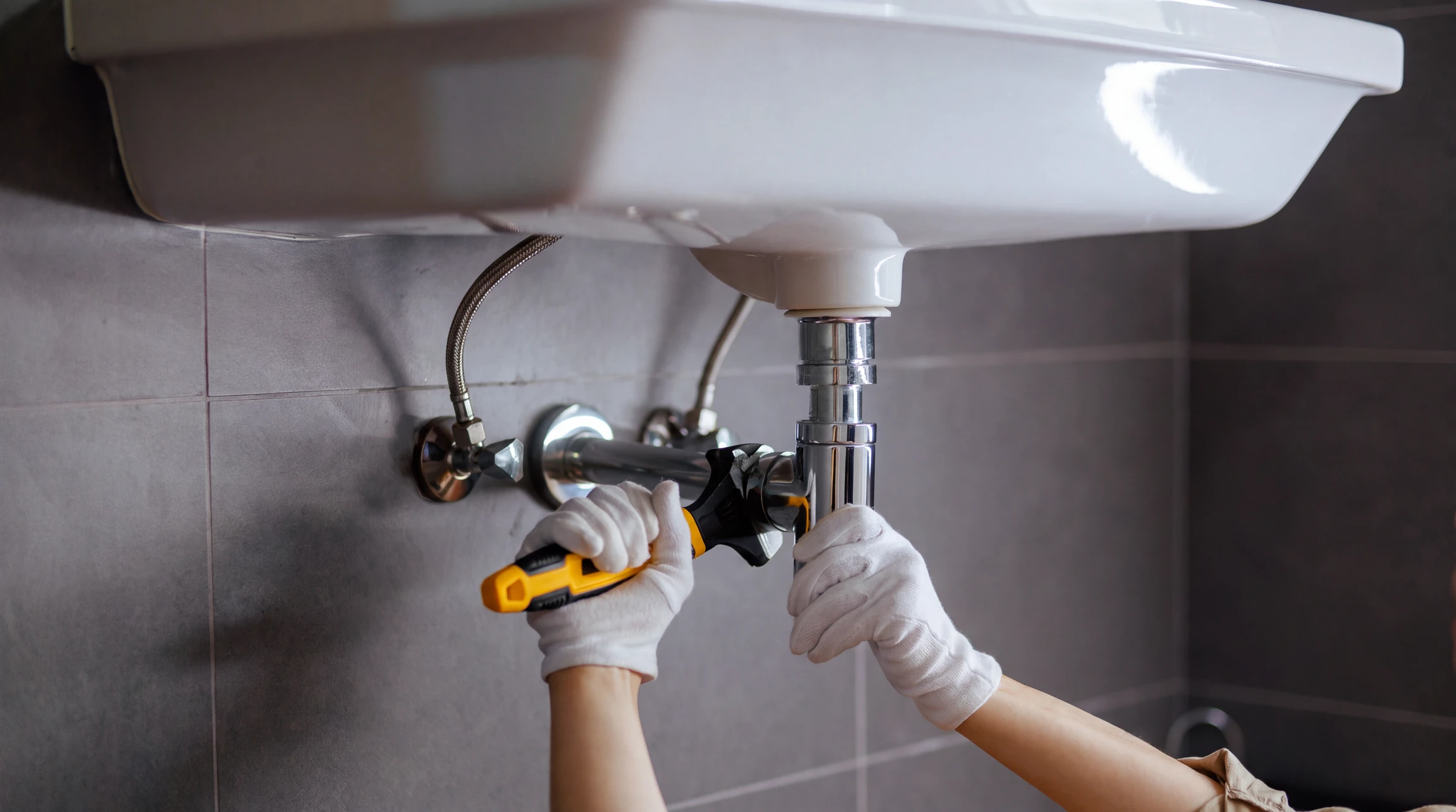 Artisan plombier en salopette installant ou réparant une cabine de douche moderne dans une salle de bain contemporaine